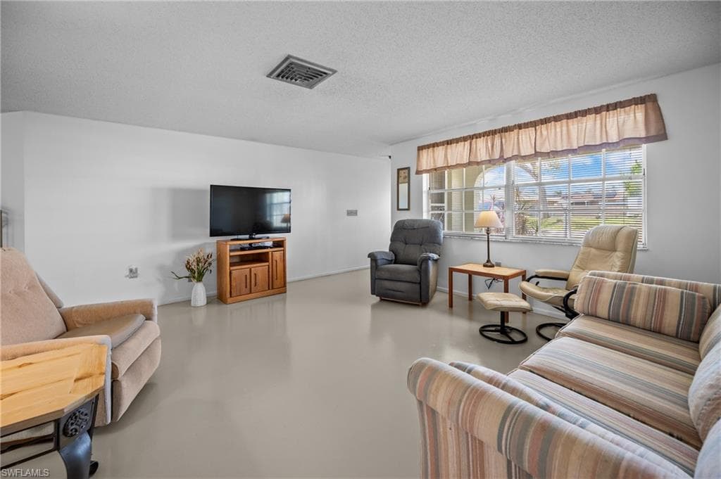 Spacious living area featuring light-colored flooring and white walls