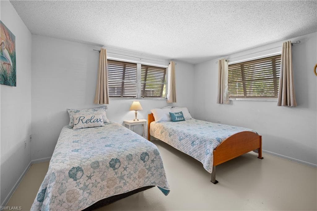 White walls with two large windows featuring horizontal blinds and neutral drapes