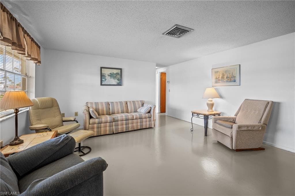 Bright living area featuring light-toned flooring, white walls, and horizontal window blinds