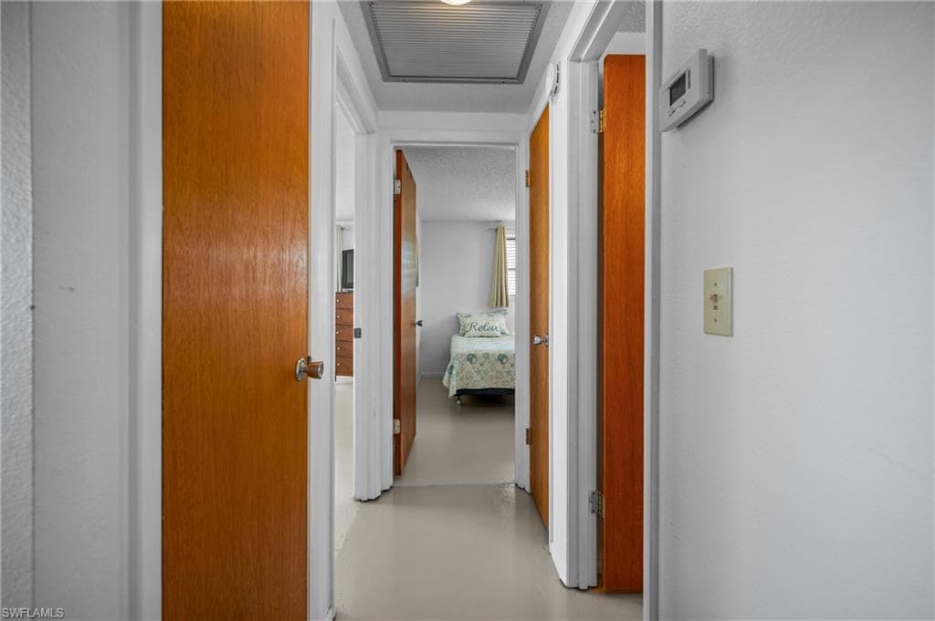 Central hallway featuring a light-toned floor, white walls, and warm wood-finish doors