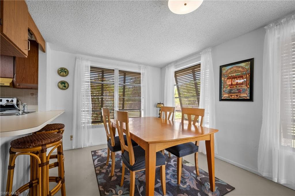 Dining area with multiple windows featuring blinds and sheer white curtains