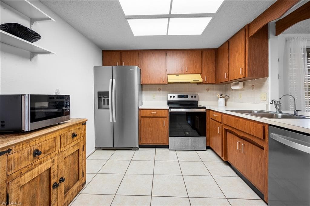 Kitchen featuring wood-finish cabinetry, light-toned countertops, and a tiled backsplash