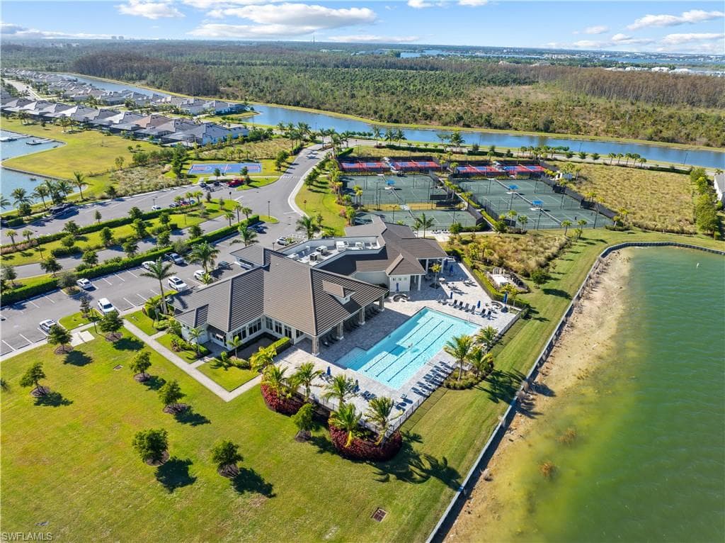 Community clubhouse featuring a swimming pool with surrounding lounge areas, extensive tennis courts, and ample parking