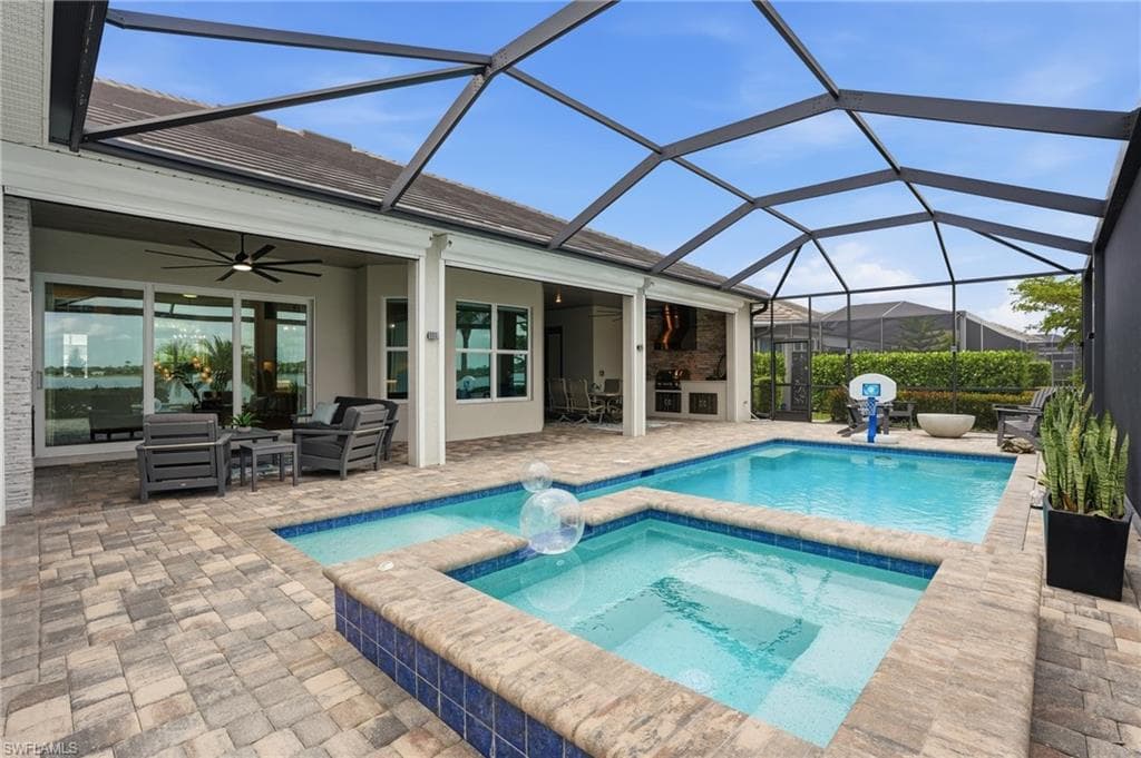 Screened outdoor living area featuring a rectangular pool, integrated spa, and spacious paver patio