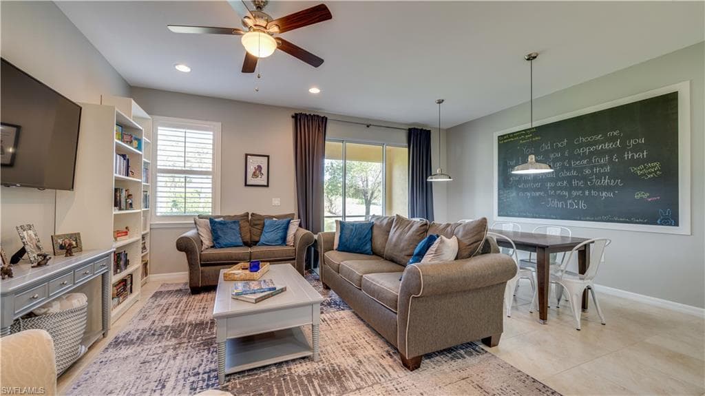 Living room with light tile patterned flooring, a wealth of natural light, and ceiling fan