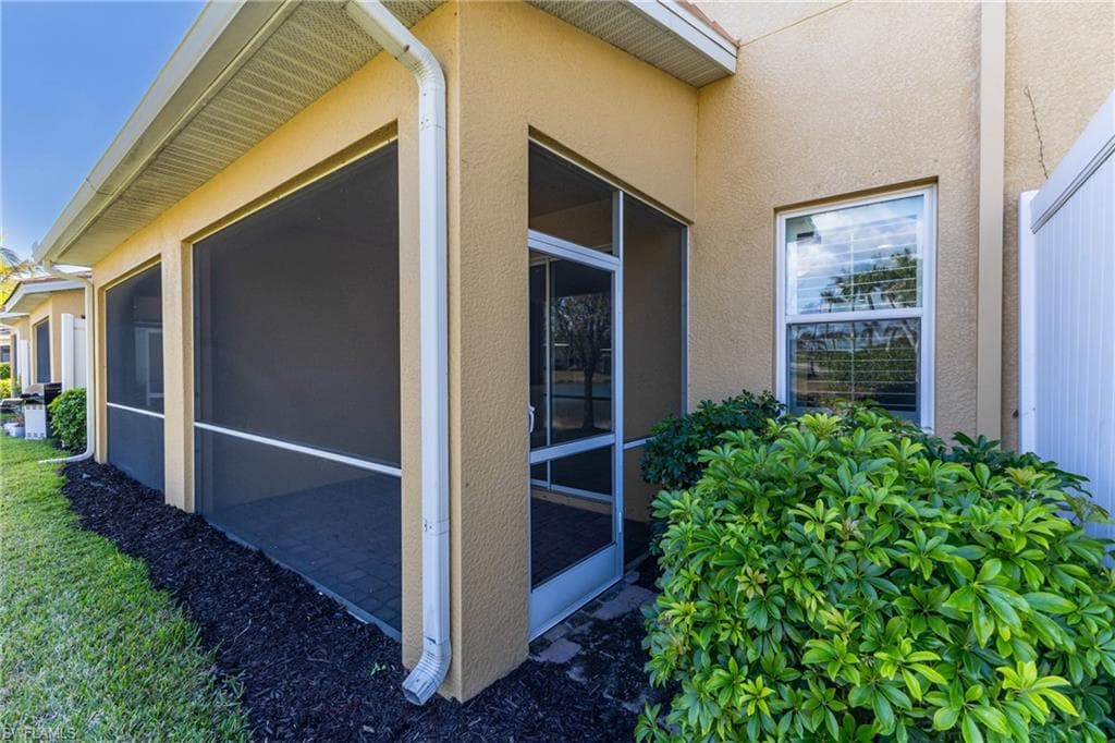View of side of home with a sunroom and stucco siding