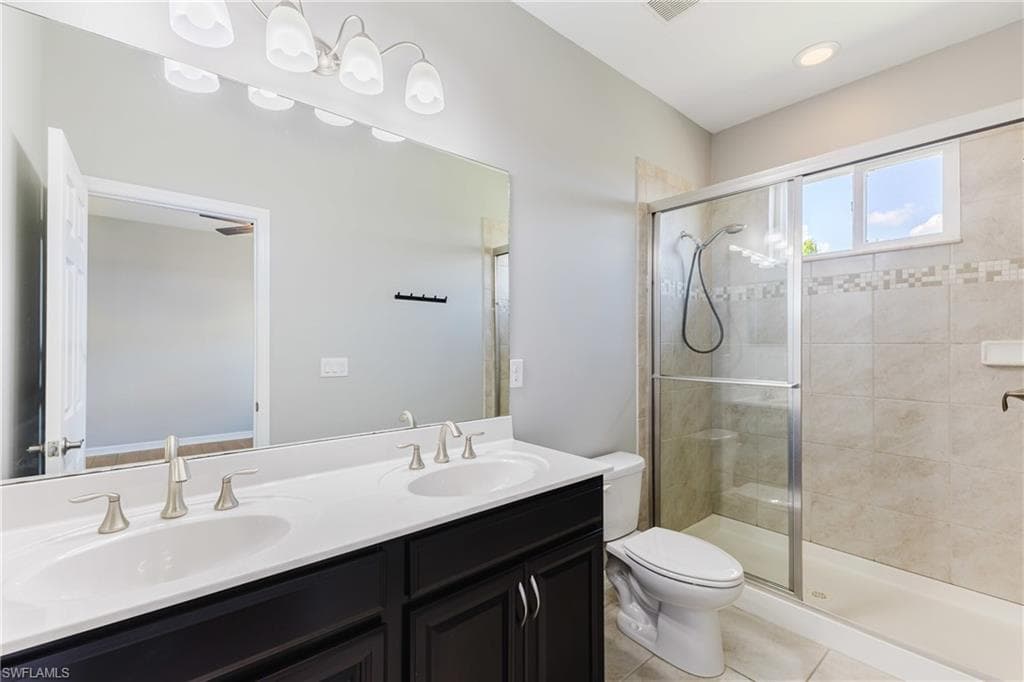 Bathroom with double vanity, a stall shower, light tile patterned floors, and recessed lighting