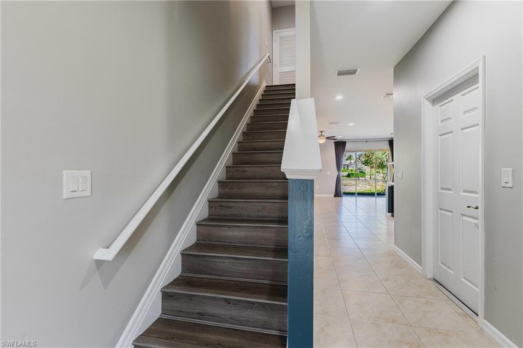 Stairs with tile patterned flooring, recessed lighting, and a ceiling fan
