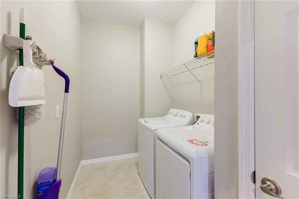 Laundry room featuring washer and dryer and light tile patterned flooring