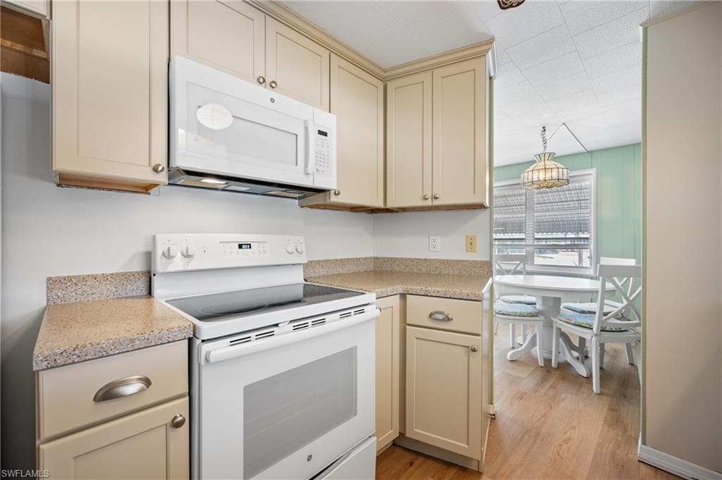 Kitchen featuring light-toned cabinetry, a white electric range, and a white over-the-range microwave