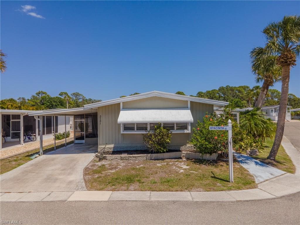 Single-story residence featuring a carport, screened porch, and a concrete driveway