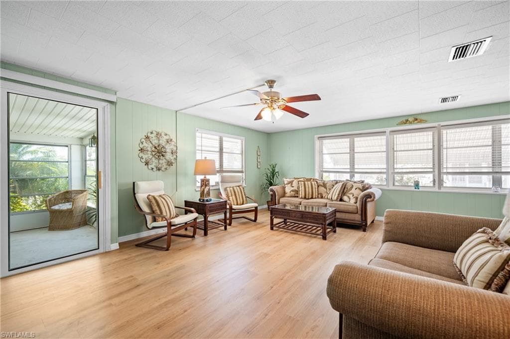 Spacious living area featuring light wood-finish flooring and ample natural light from multiple windows