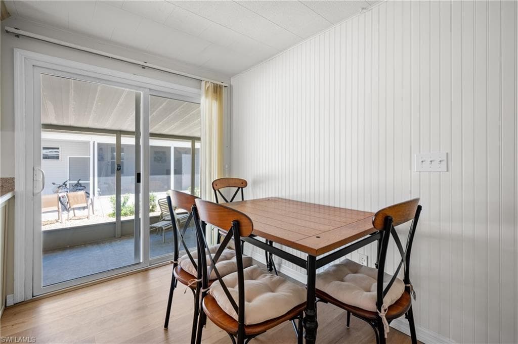 Sliding glass doors opening to a screened patio, featuring wood-finish flooring, vertical plank wall paneling, and a drop ceiling