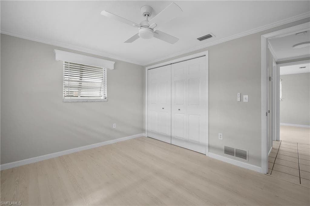 Room featuring light wood-finish flooring, neutral gray walls, and white trim