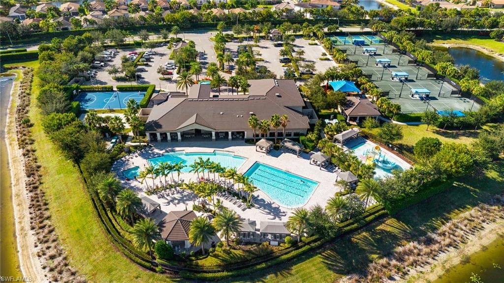 Expansive community amenity center featuring multiple swimming pools, extensive patio areas, a large clubhouse building, numerous tennis courts, and a basketball court