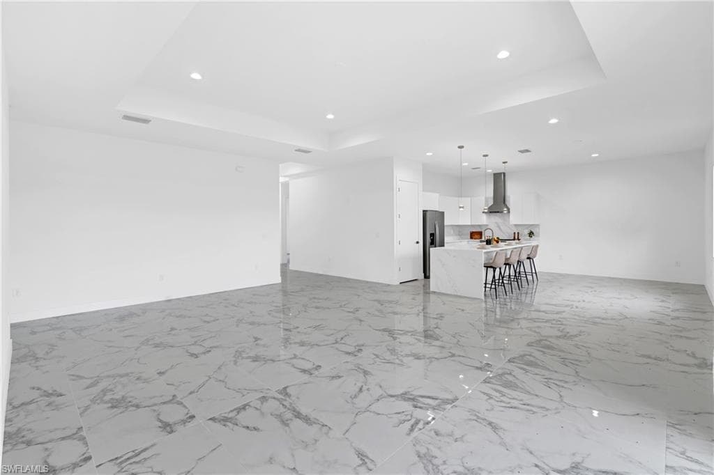Open-concept kitchen and living area featuring large format marble-look tile flooring