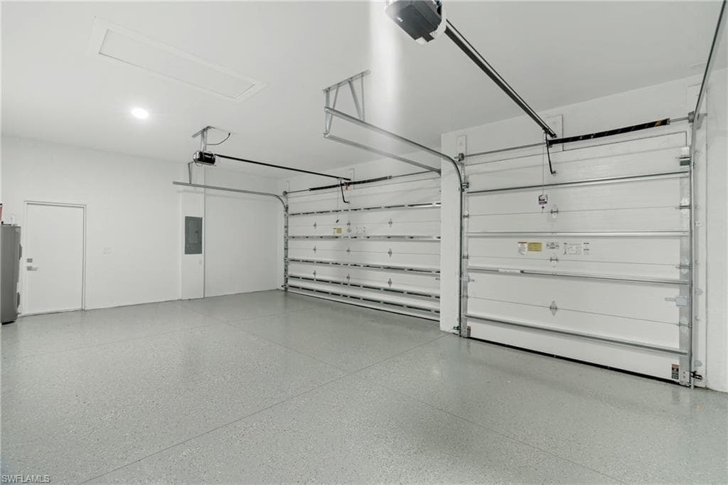 Three-car garage featuring a speckled epoxy floor coating, two overhead garage doors, an access panel, and a side access door