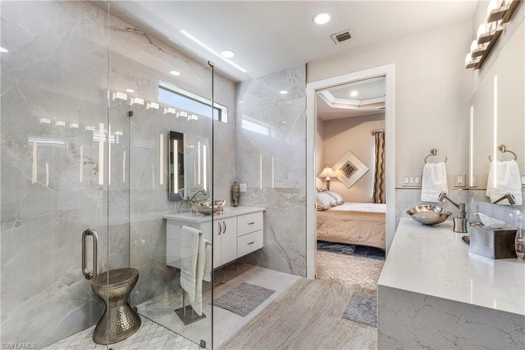 Ensuite bathroom with ensuite bathroom, recessed lighting, tile walls, visible vents, and a marble finish shower