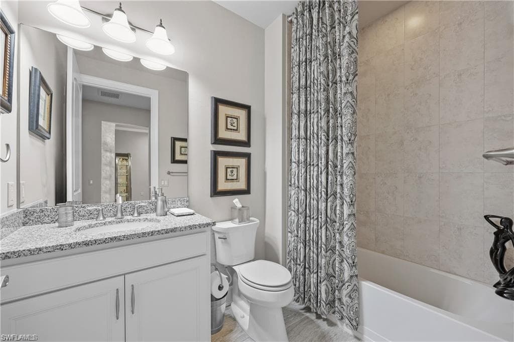 Bathroom featuring vanity and shower / bathtub combination with curtain