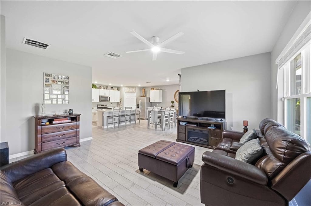Open-concept living space featuring wood-finish flooring, a contemporary ceiling fan, and recessed lighting