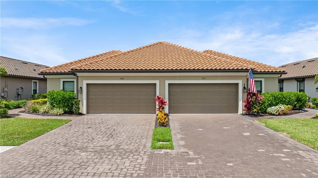 Duplex residence featuring a tile roof and two distinct paver driveways