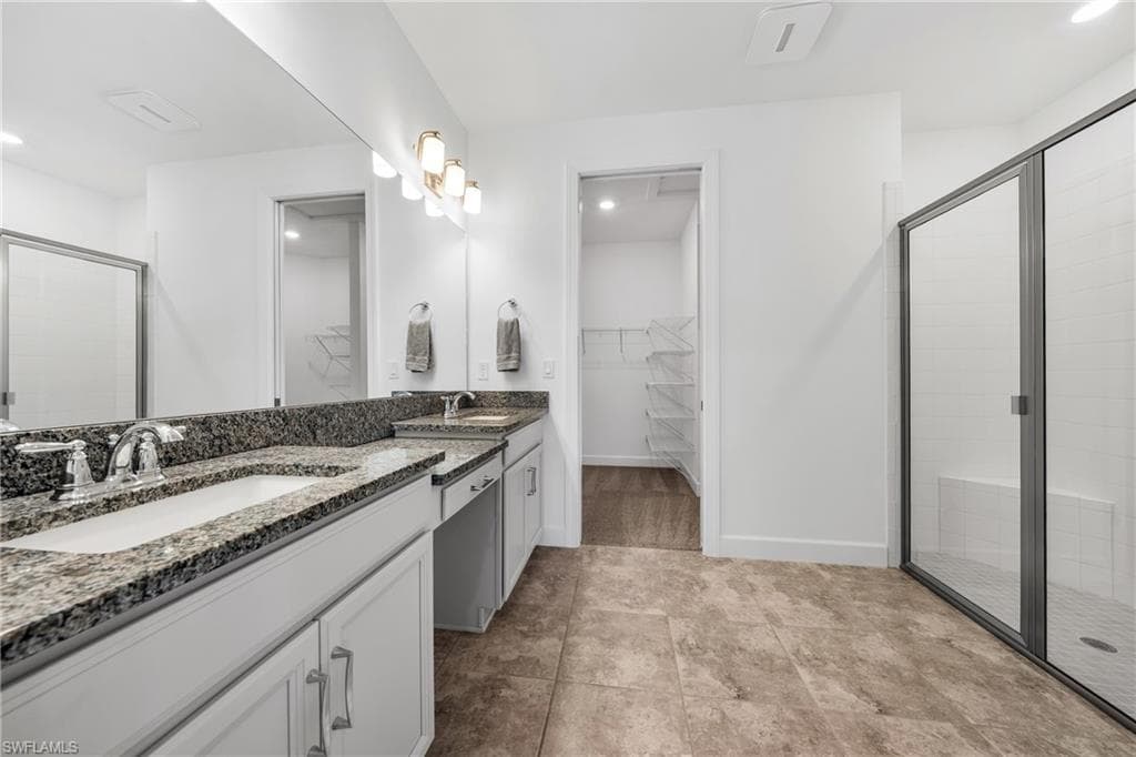 Bathroom featuring a dual vanity with granite countertops, undermount sinks, and chrome fixtures