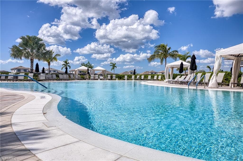 Expansive resort-style swimming pool @ main clubhouse featuring a curved perimeter, white coping, and surrounding lounge chairs