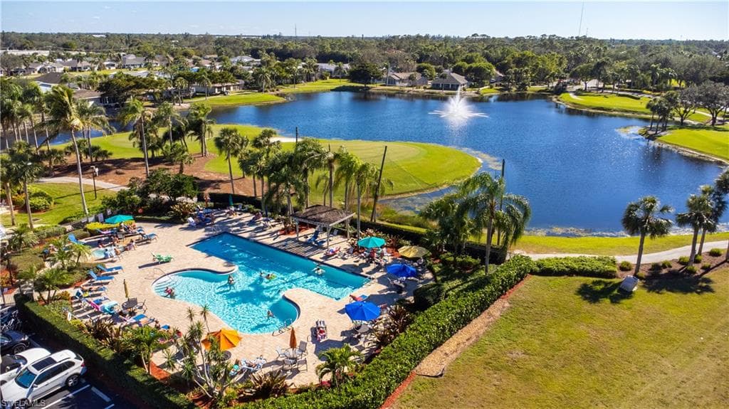 Resort-style pool area featuring multiple lounge chairs and umbrellas, surrounded by lush tropical landscaping