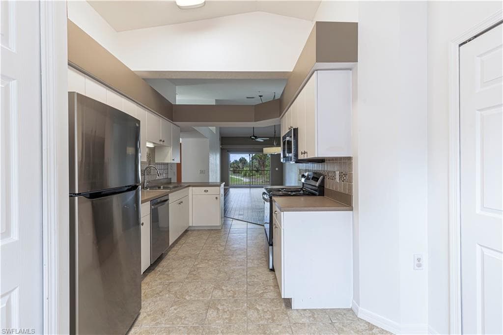 Galley kitchen featuring white cabinetry, light-toned countertops, and tile flooring