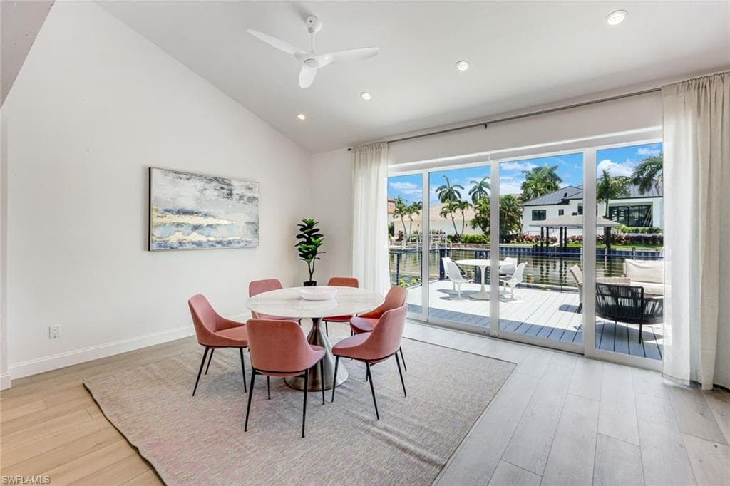 Spacious room with light wood-finish flooring and a vaulted ceiling featuring recessed lighting and a ceiling fan