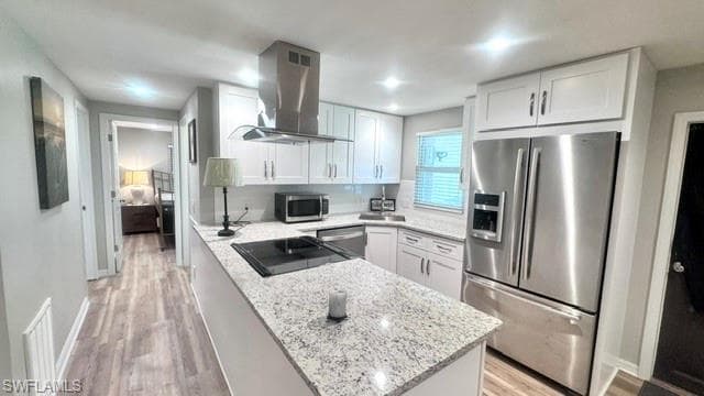 Modern kitchen featuring a central island with a built-in cooktop, white shaker cabinetry, stainless steel appliances, and granite countertops