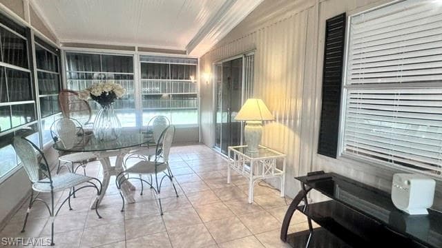 Screened patio featuring a sliding glass door, tiled flooring, and a corrugated exterior wall