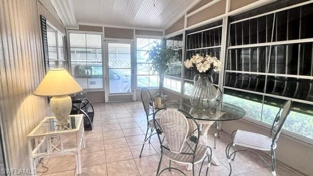 Enclosed sunroom featuring tile flooring, white vertical siding, and multiple windows with security bars