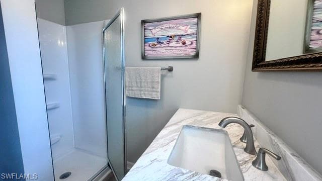 Bathroom featuring a white shower stall with a frosted glass door, a vanity with a light-colored countertop, an undermount sink, and a brushed nickel faucet