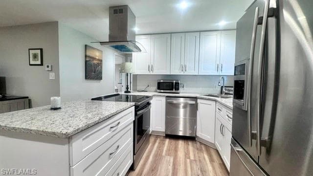 Modern kitchen featuring white shaker cabinetry, stainless steel appliances, speckled stone countertops, and wood-finish flooring