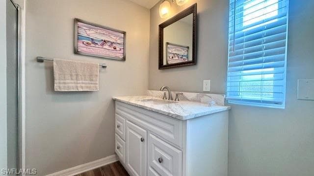Bathroom vanity with white cabinetry, a marble-patterned countertop, and an undermount sink
