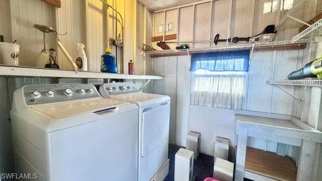 Dedicated utility room featuring a washer and dryer, wall-mounted shelving, and a built-in workbench