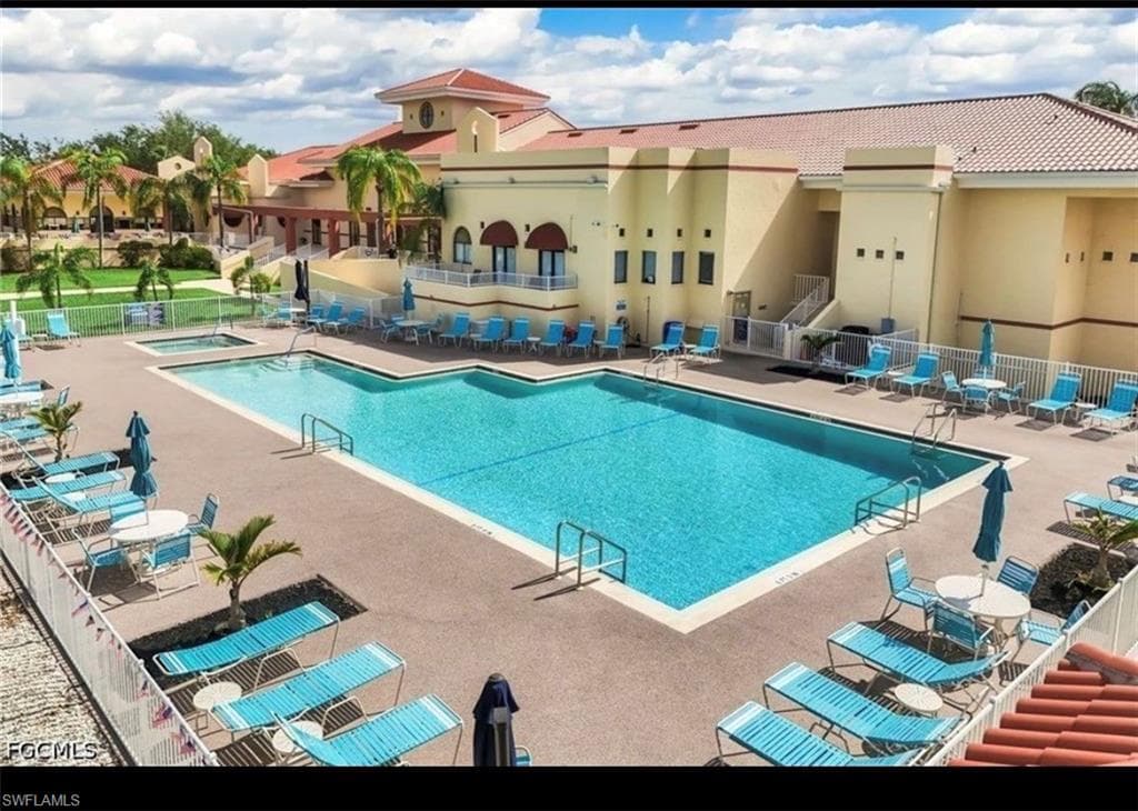 Community swimming pool featuring a rectangular design, adjacent spa, and surrounding lounge areas