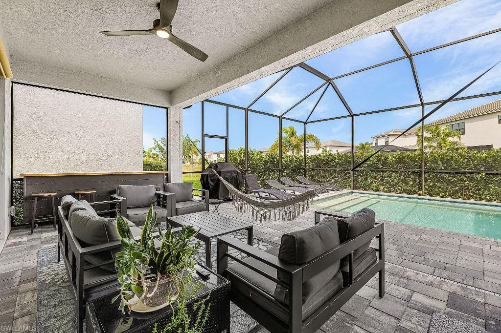 Screened-in outdoor living area featuring a covered patio, ceiling fan, and a built-in bar