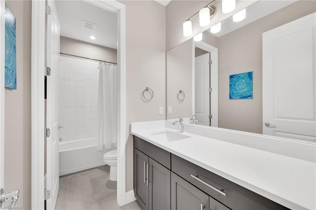 Bathroom featuring a dual-sink vanity with white countertops, dark cabinetry, and brushed nickel hardware