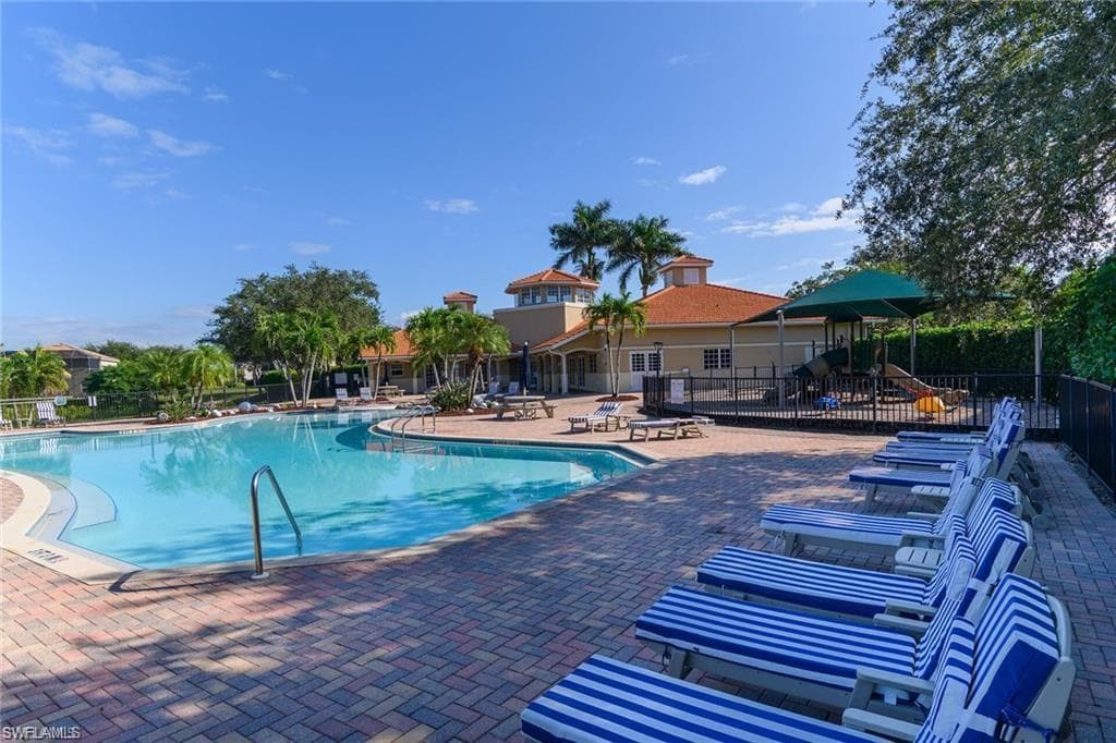 Expansive pool area featuring a large, blue-tiled swimming pool and surrounding paver decking