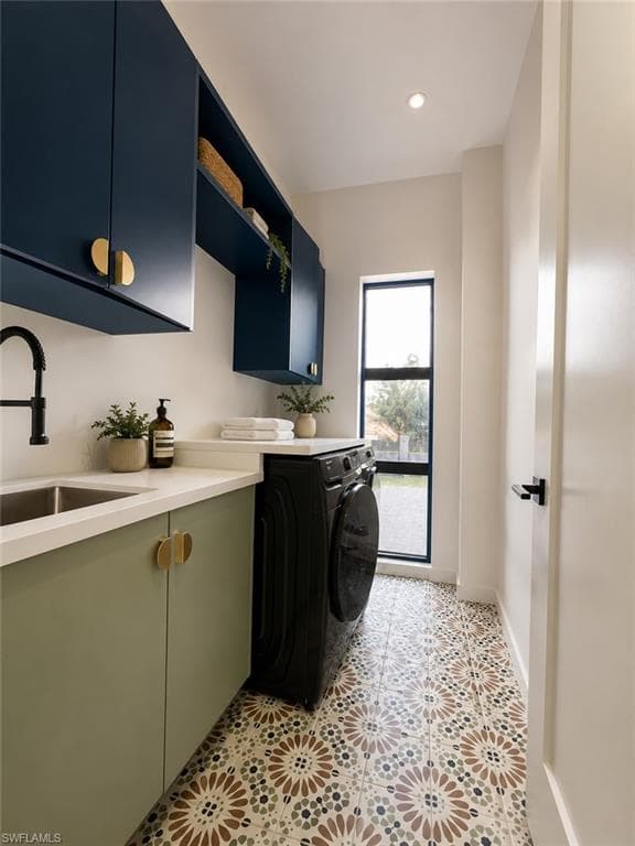 Laundry room featuring patterned floor tiling, built-in cabinetry with gold-toned hardware, a sink with a black faucet, and a window with black trim