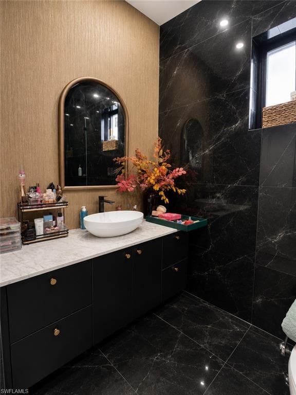 Contemporary bathroom featuring a black vanity with gold hardware, a white vessel sink, and a light-toned countertop