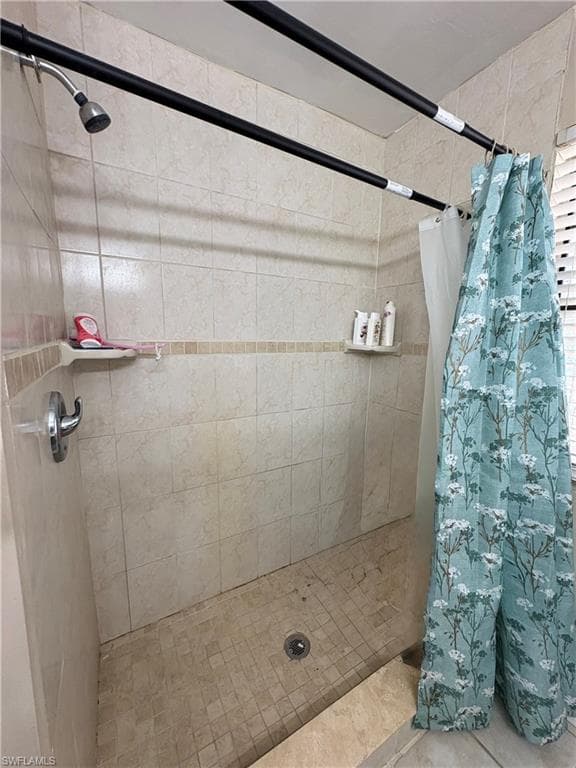 Tiled shower enclosure featuring a fixed showerhead and built-in shelving