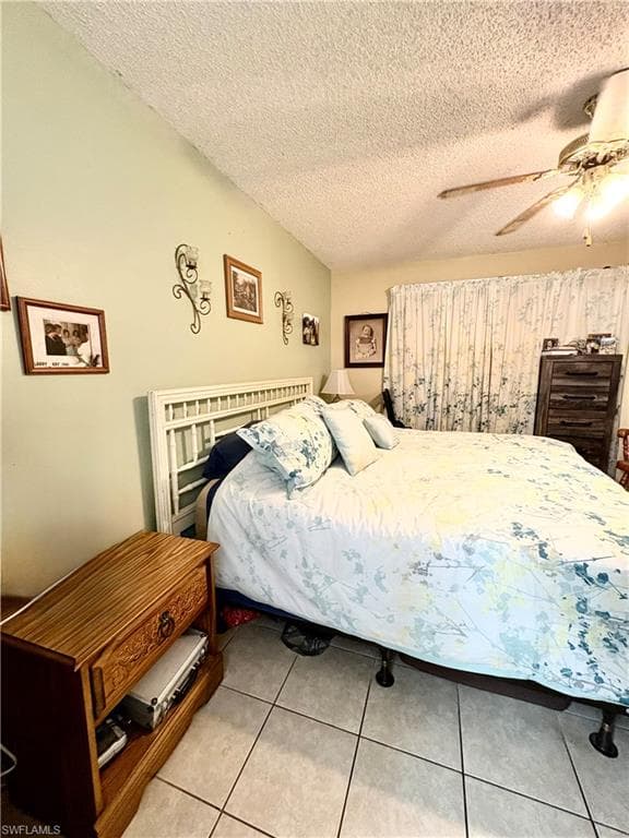 Room featuring tiled flooring, a sloped ceiling, and a ceiling fan with light fixture