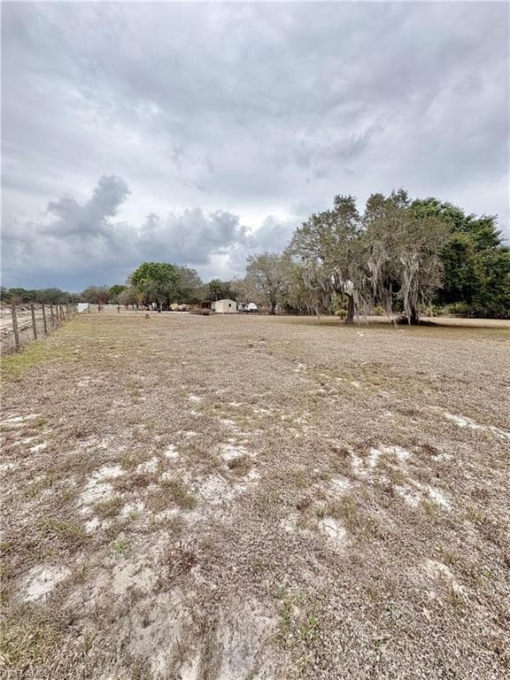 Expansive open land featuring mature trees and partial fencing