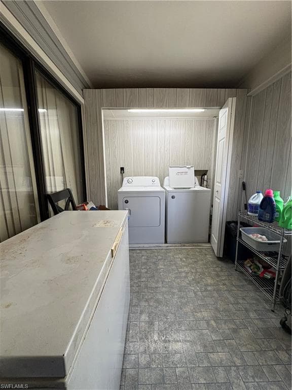 Dedicated laundry area with durable flooring, wood-finish paneling, and an overhead light fixture