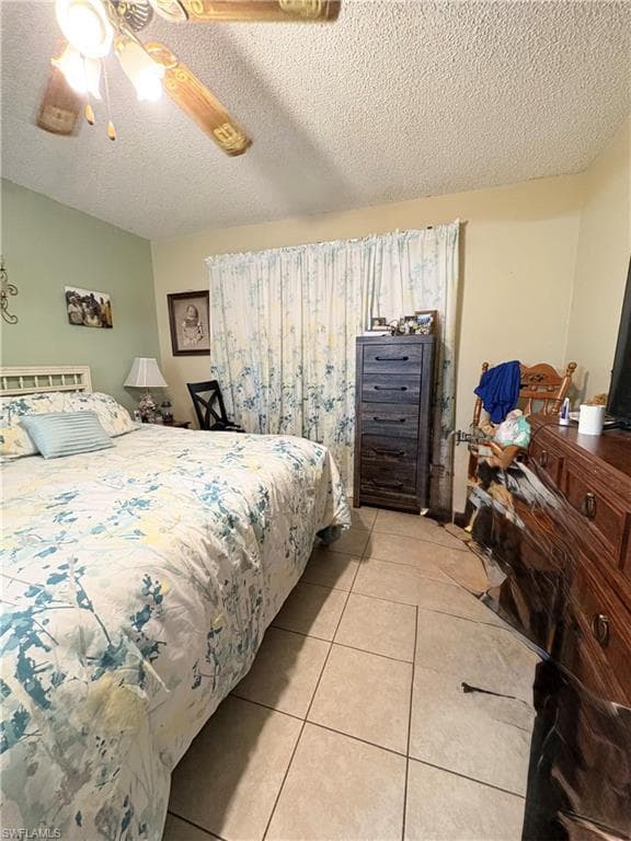 Bedroom featuring tile flooring, a ceiling fan with integrated lighting, and textured ceilings