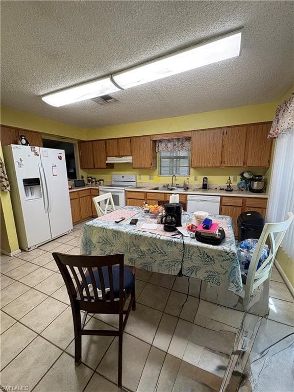 Kitchen featuring light wood cabinetry and a white appliance suite