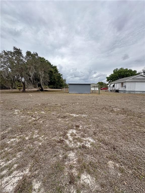 Expansive lot featuring a detached storage shed, mature trees, and a partial view of a residential structure